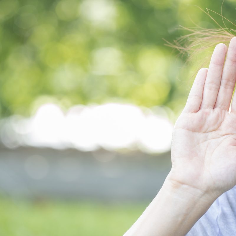 Woman holds her hand near ear with symptom of hearing loss